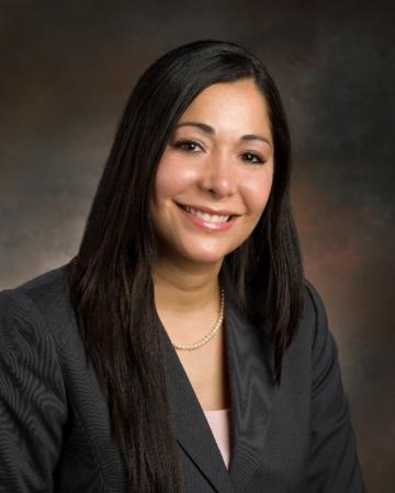 Professional Headshot. A Hispanic woman with long, straight dark hair smiles at the camera.