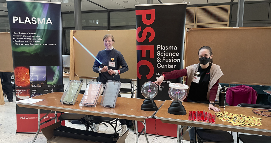 Two women with plasma demos at table in front of PSFC signage