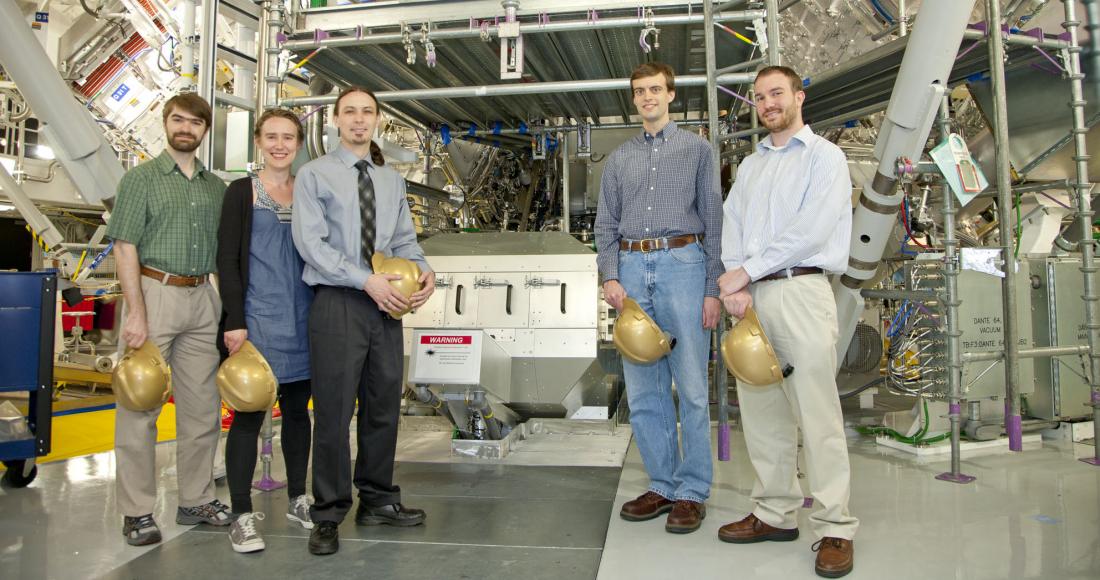 4 men and 1 woman standing in front of machine