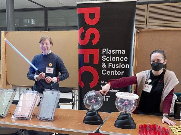 Two female graduate students presenting plasma demos at a table